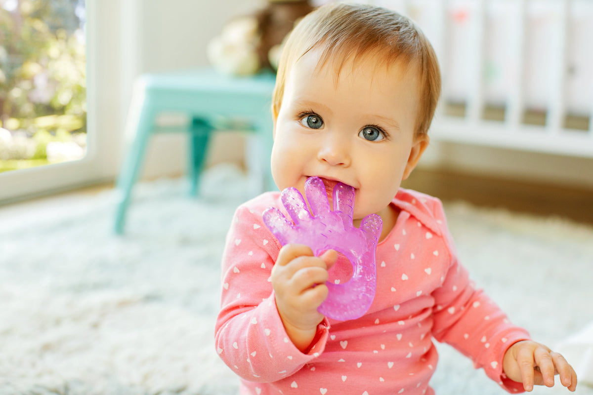 Bebé sujetando una taza rosa en el suelo